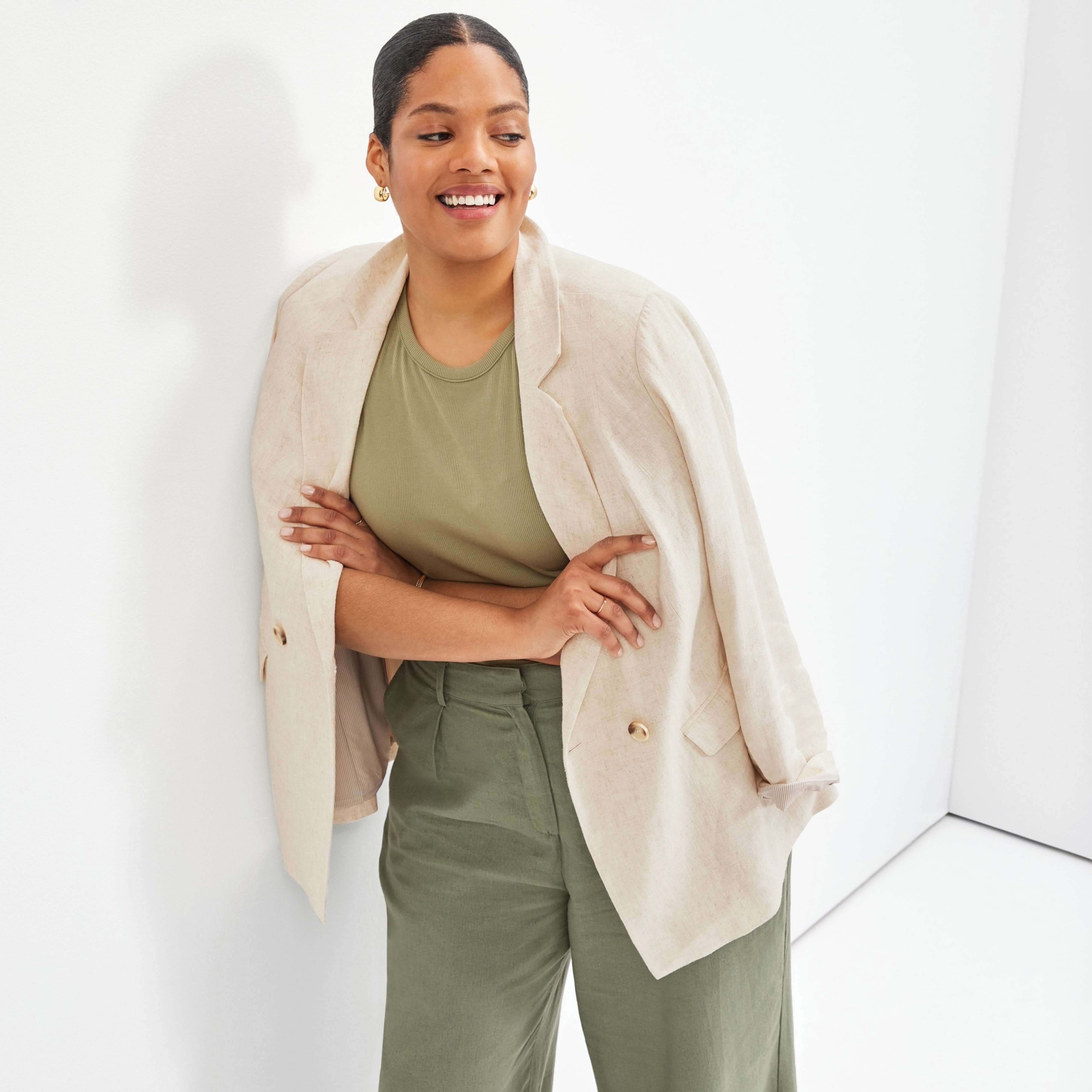 Plus-size model wearing women’s Stitch Fix clothing, including a beige blazer, olive green shirt and dark green pants.