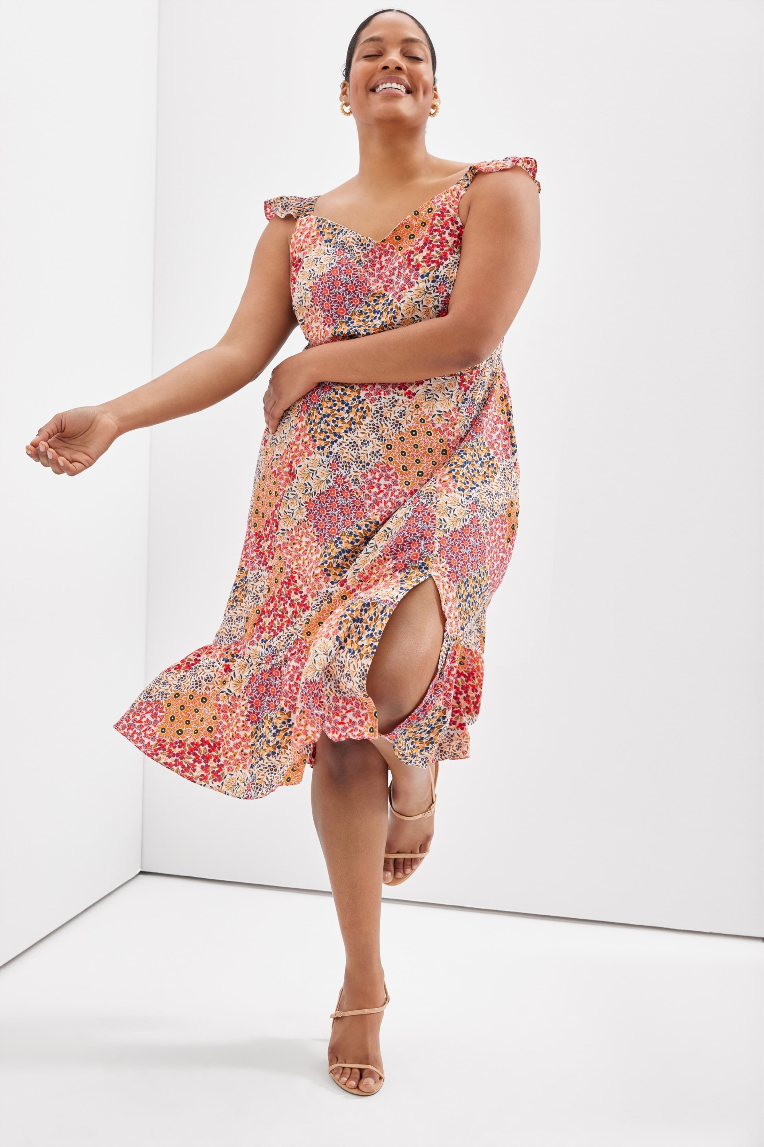 Plus-size model wearing women’s Stitch Fix clothing, including a patterned midi dress and heel sandals.