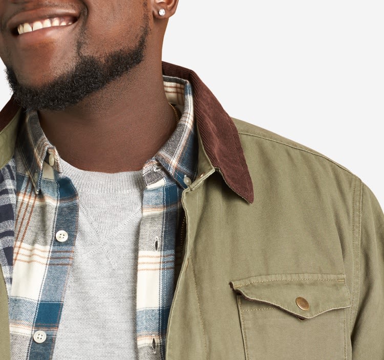 Grey tee, plaid shirt and olive green jacket with brown collar.