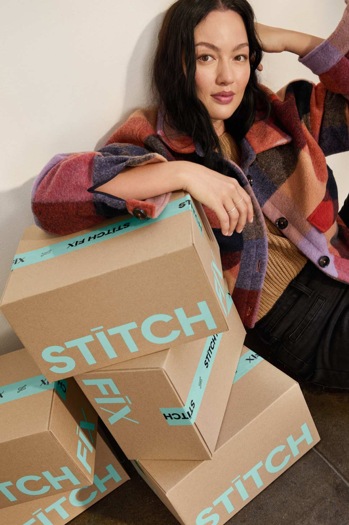 Model wearing Stitch Fix women’s clothes including colorful jacket and black pants.