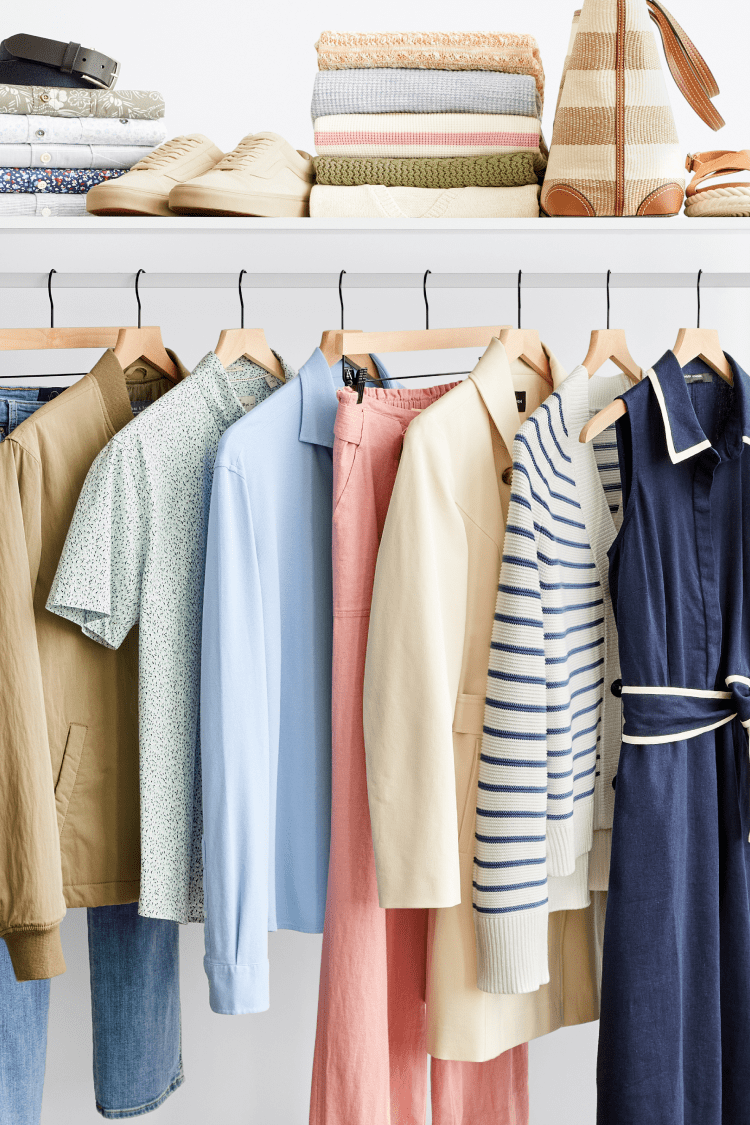 Stitch Fix clothes hanging on a rack and folded on top including jackets, sandals, mules, purses, dresses and jeans.